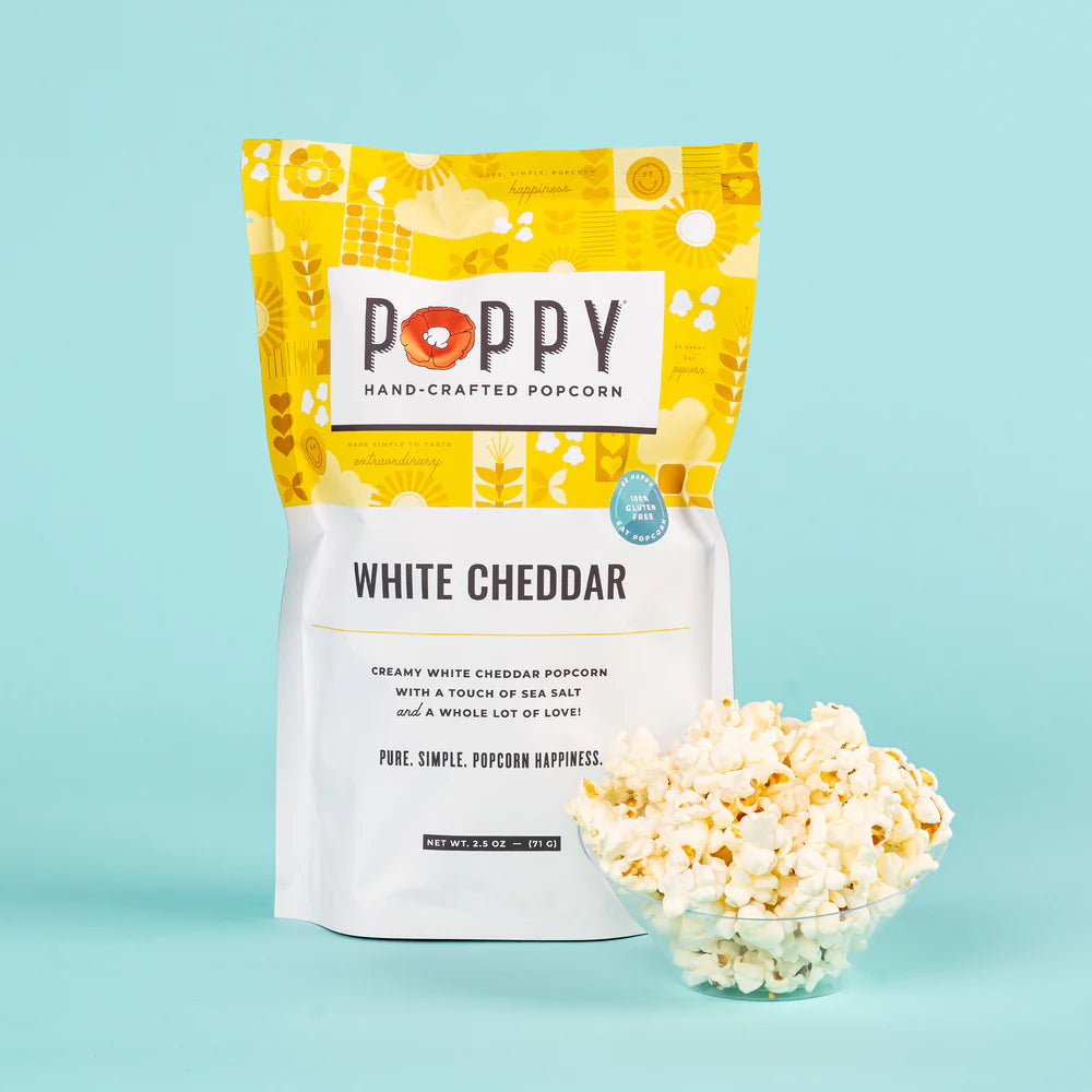 Poppy White Cheddar Hand-Crafted Popcorn bag with a bowl of cheesy popcorn