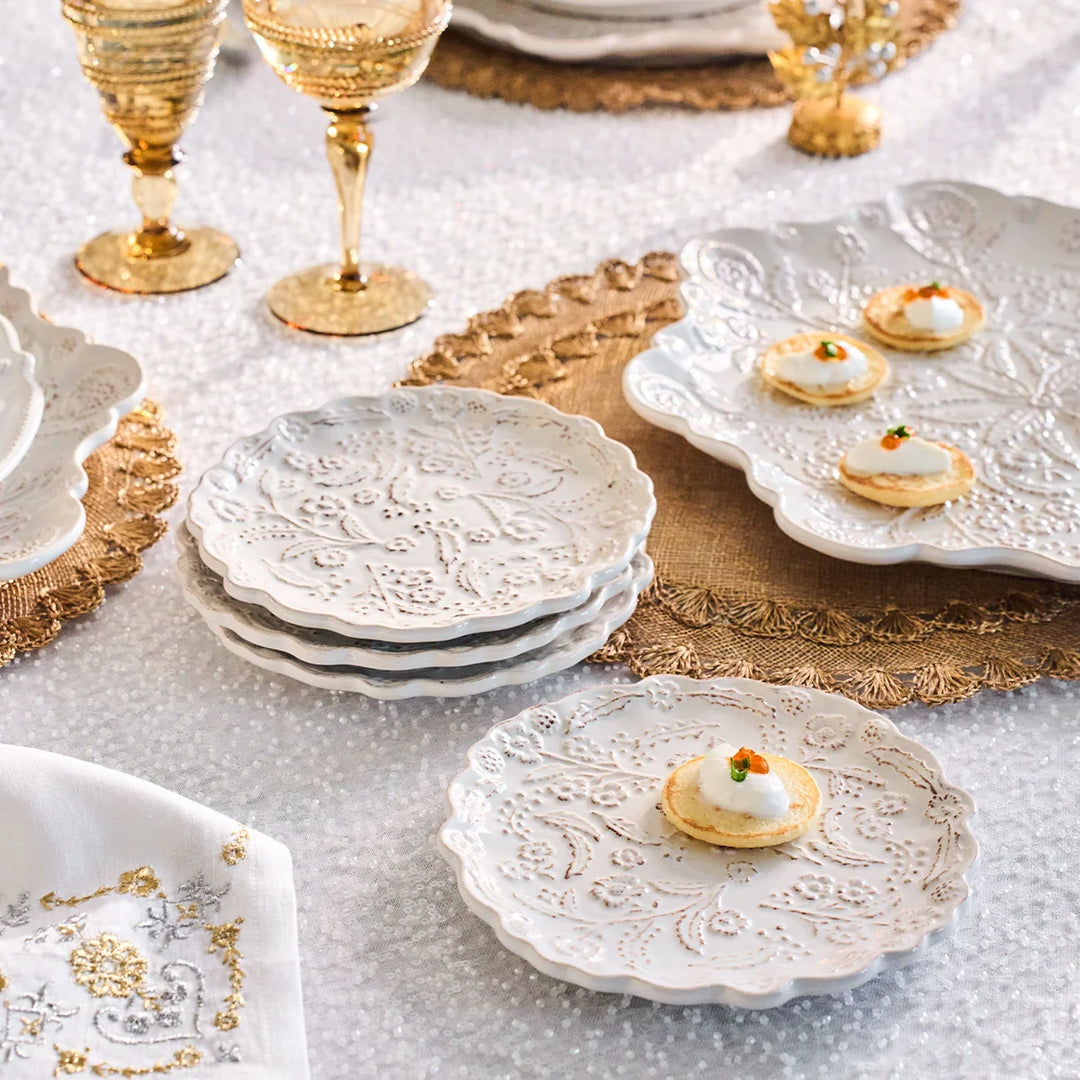 White floral appetizer plates with raised floral detailing styled with small appetizers on an elegant entertaining table.