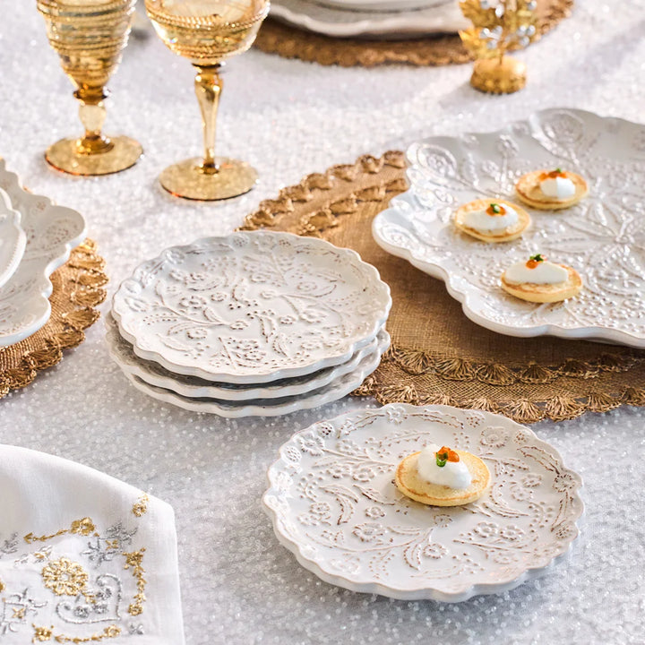 White floral appetizer plates with raised floral detailing styled with small appetizers on an elegant entertaining table.
