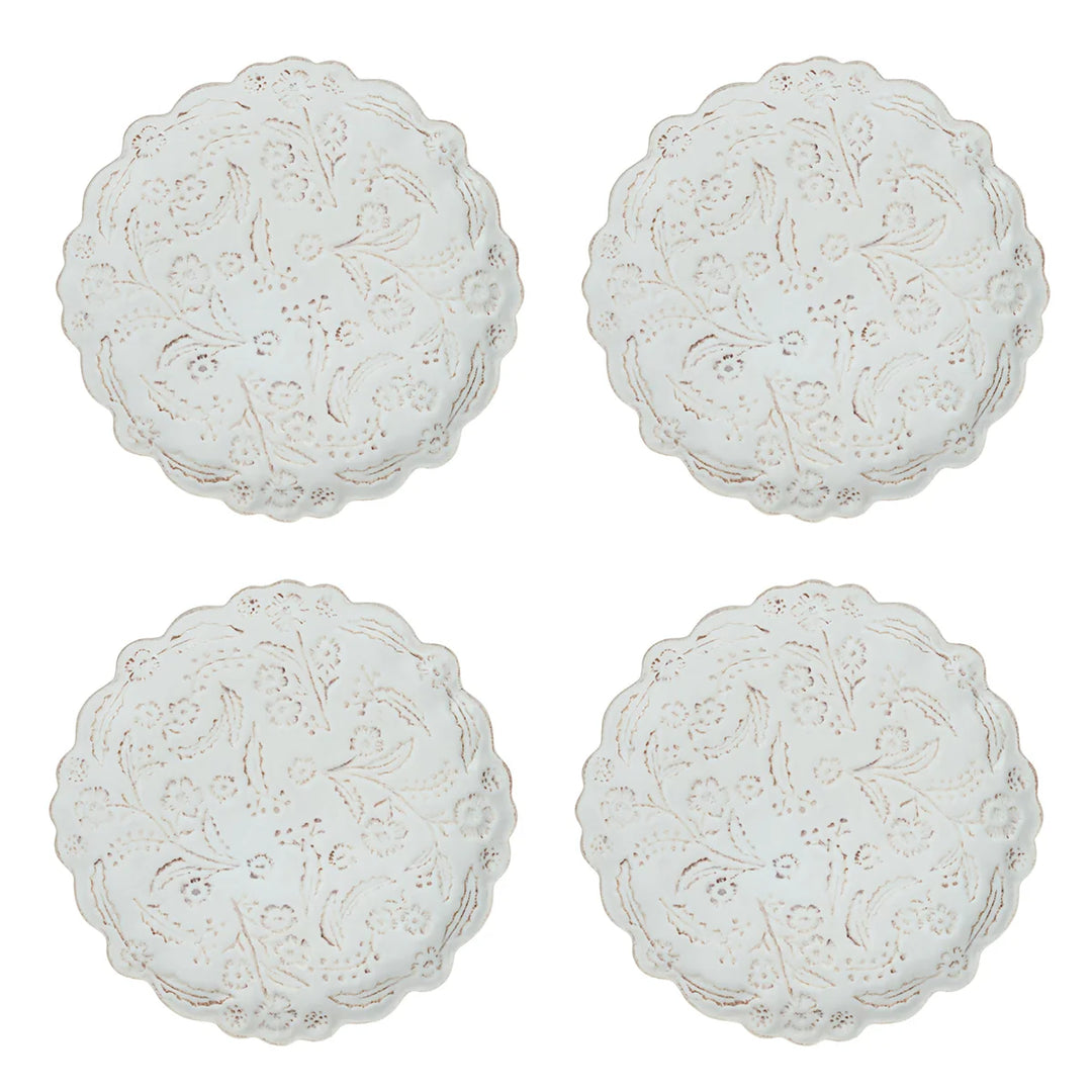 Set of four white floral appetizer plates featuring scalloped edges and raised botanical detailing.