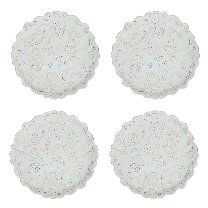 Set of four white floral appetizer plates featuring scalloped edges and raised botanical detailing.