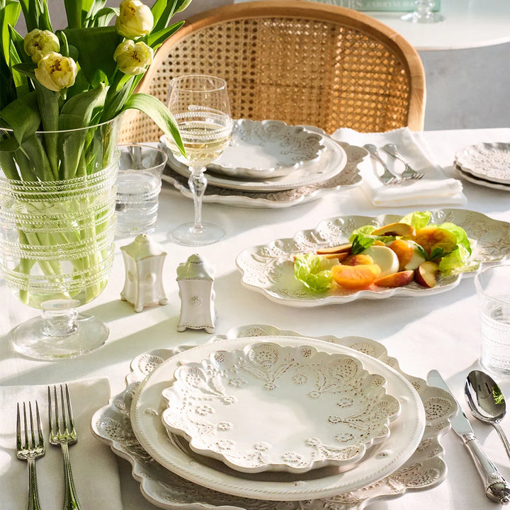 White floral round serving platter displayed with coordinating scalloped dinnerware on a bright spring tablescape with tulips.