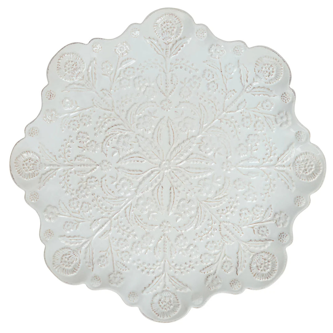 White floral round serving platter with scalloped edges and intricate raised botanical detailing.