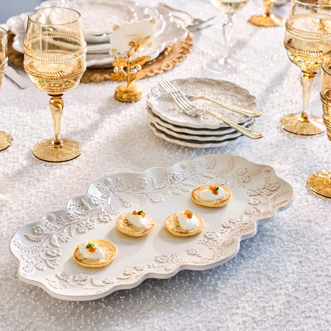 White floral serving platter with raised botanical details used to serve small appetizers on an elegant table.