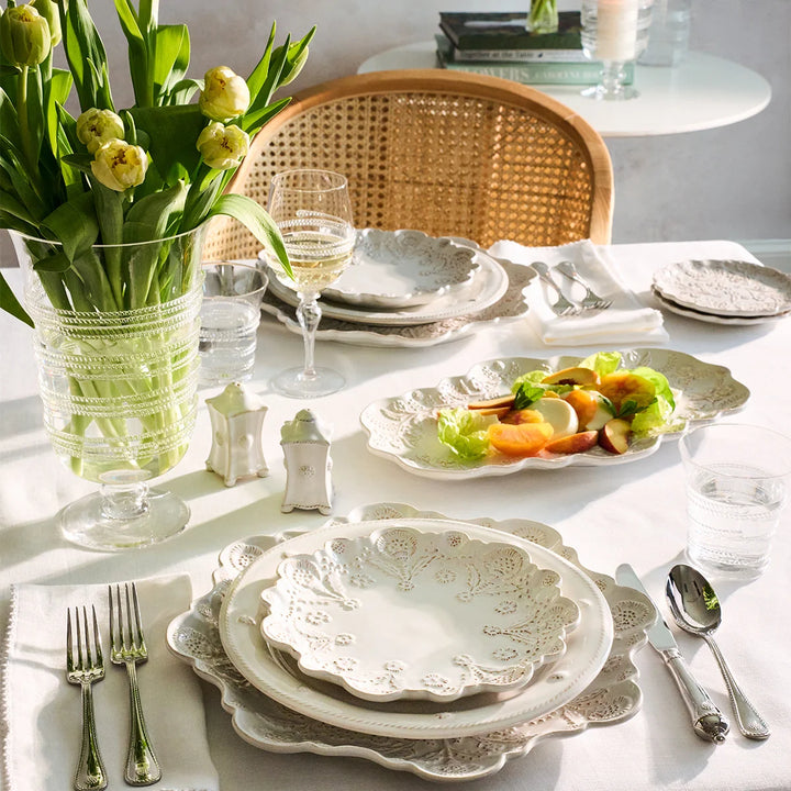 White floral serving platter styled with fresh fruit on an elegant spring tablescape with white dinnerware and tulips.