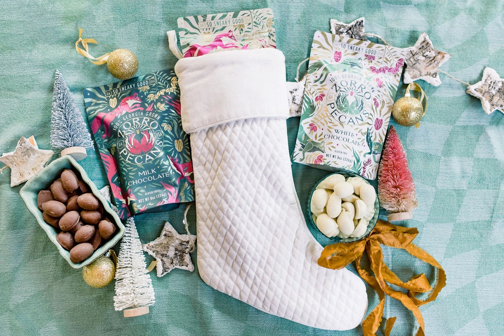 Zorro Milk Chocolate Covered Pecans displayed alongside white chocolate pecans, a Christmas stocking, and festive holiday decorations.