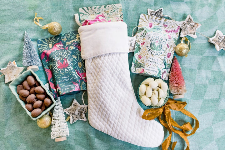 Zorro Milk Chocolate Covered Pecans displayed alongside white chocolate pecans, a Christmas stocking, and festive holiday decorations.