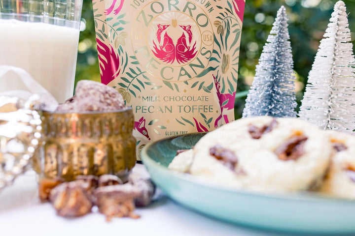 Zorro Milk Chocolate Pecan Toffee displayed with holiday sweets, a glass of milk, and miniature Christmas trees.