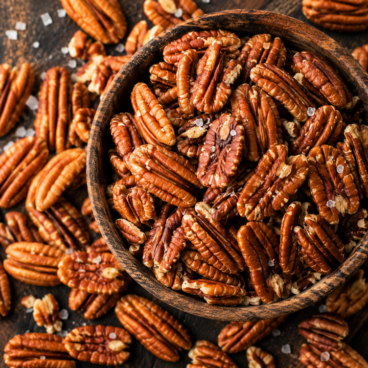 Close-up of Zorro Pecans Roasted &amp; Lightly Salted premium Georgia pecans with a delicate salt coating in a rustic wooden bowl.