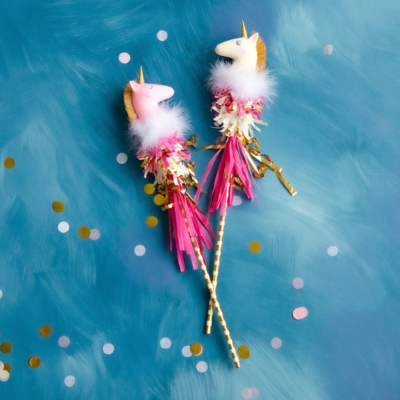 Pink and white unicorn magic wands with gold striped handles, fluffy marabou feathers, colorful paper fringe, and gold ribbon accents.